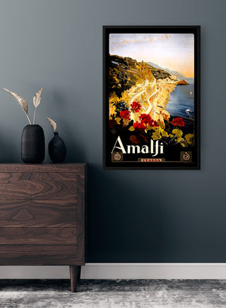 Framed Amalfi Vintage Plakat on a dark wall above a wooden dresser, featuring coastal scenery and flowers.