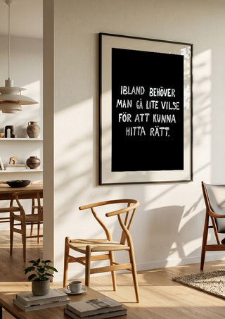 Gå vilse by Grafik bageri in a black frame in a bright dining room with wooden chairs