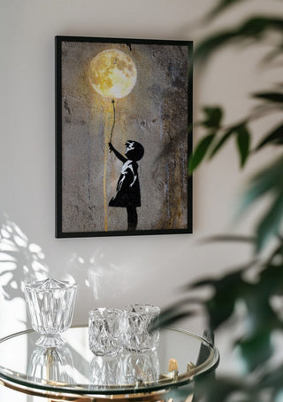 Moon Balloon by Decker Studios in a black frame above a glass table with crystal glassware