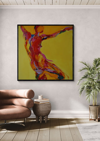 Reaching Figure by René J in a black frame above a tan leather chair beside a potted plant