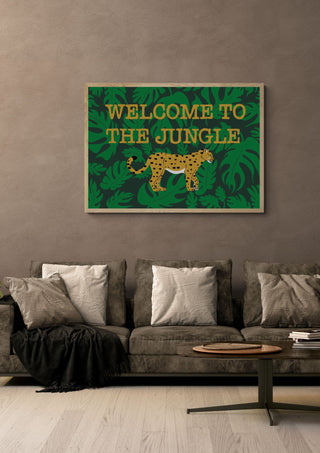 Welcome to the jungle by Lisen Vennesland in a light wood frame above a grey sofa with cushions