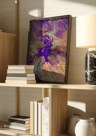 Violet Drift by Da Winters in a dark frame on a wooden shelf beside books and a lamp