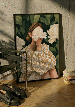 Behind the Peony by Martina Karlsson in a black frame leaning against a concrete wall by a steel chair