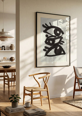 Abstract line art eyes 3 by ThingDesign in a black frame in a bright dining room with wooden chairs
