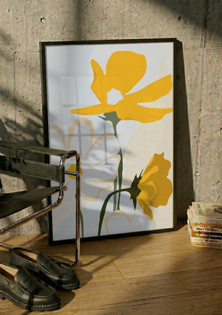 Yellow Flowers by ThingDesign in a black frame leaning against a concrete wall by a steel chair