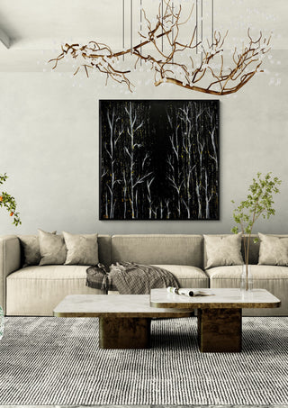 White Birches at Night by Marcel Herrmann in a black frame above a cream sofa under a branch chandelier