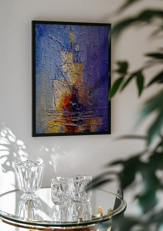 Ships in Violet and Gold by Justyna Kopania in a black frame above a glass table with crystal glassware
