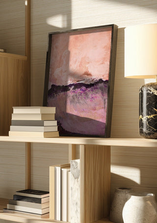 expressive landscape by Iris Lehnhardt in a dark frame on a wooden shelf beside books and a lamp
