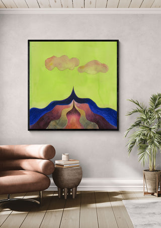 Mountain Under a Green Sky by Shimmering Ugly in a black frame above a leather armchair beside a potted palm