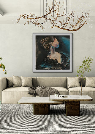 The Rich Lady by Christin in a black frame above a beige sofa under a branch chandelier