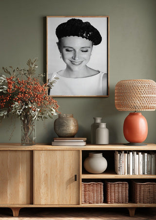 The French girl by Bettinafloorphoto above a wooden sideboard on a sage green wall