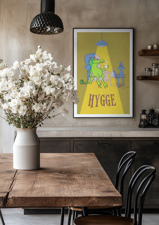 Hygge Crocodile - Yellow by Elisa Albanelli in a black frame above a rustic table with white flowers