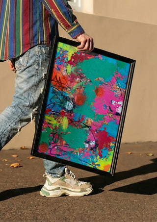 paint it loud by hazelart carried in a black frame along a sunny street