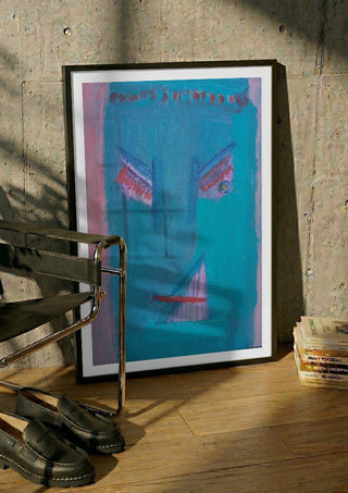 The Joy - De Vreugde by Motaz Nader in a black frame leaning against a concrete wall by a steel chair