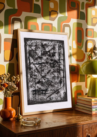 Black Field by David Pernecker in a wooden frame on a sideboard against a retro patterned wall