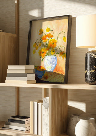 Poppies And Peaches by Deblina Dey in a dark frame on a wooden shelf beside books and a lamp