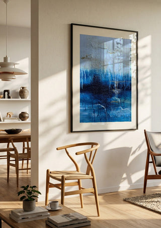 Rising Light by Sabine Halbrock in a black frame in a bright dining room with wooden chairs