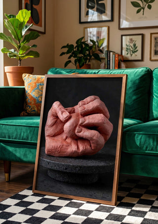 Hold Me - Terracotta Hands by Ammar in a wooden frame beside a green velvet sofa on a chequered floor