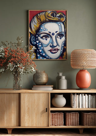 Pinup Girl by Okiana above a wooden sideboard on a sage green wall