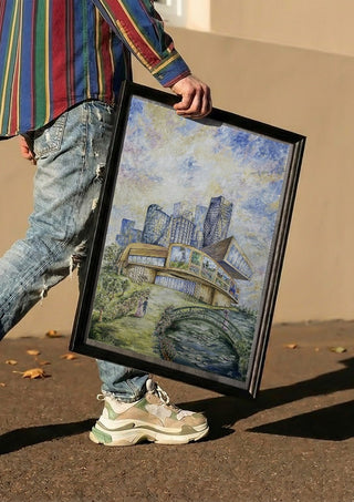 Modern Monet by Ramona’s art carried in a black frame along a sunny street