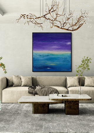Fragment of Space by Marina Agre in a black frame above a beige sofa under a branch chandelier