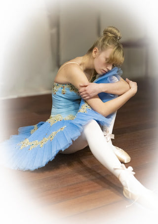 The Russian ballet dancer by Bettinafloorphoto - a dancer in a pale blue tutu seated on a wooden floor