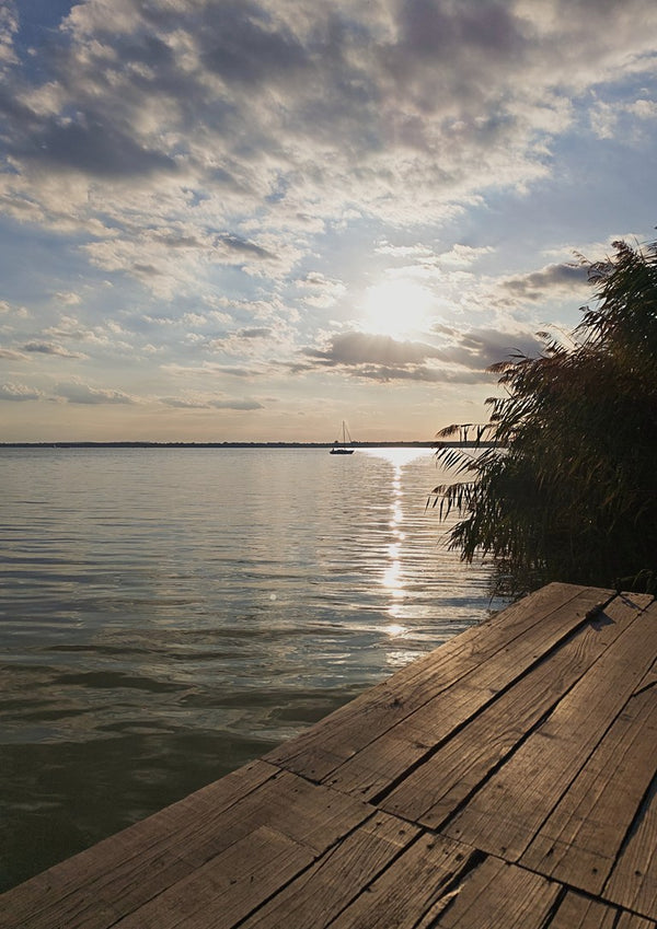 Sunset at the Lakeside Dock by Bora Kőhalmi - a wooden dock on Lake Balaton with a low sun and a silver path on the water