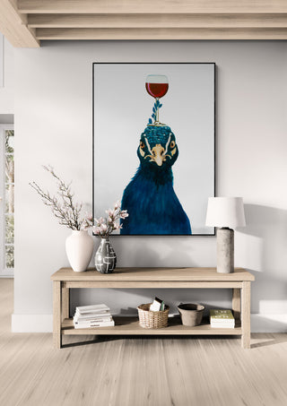 Framed art of a peacock balancing a glass of wine, displayed above a console table in a stylish living room.