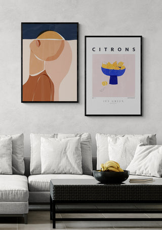 Framed poster of lemons in a blue bowl labeled "CITRONS" hanging above a modern sofa.