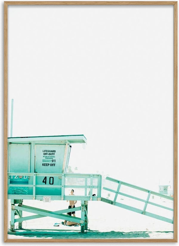 Minimalist photo of a pastel blue lifeguard tower marked "40" on a bright beach, with a lone figure underneath.