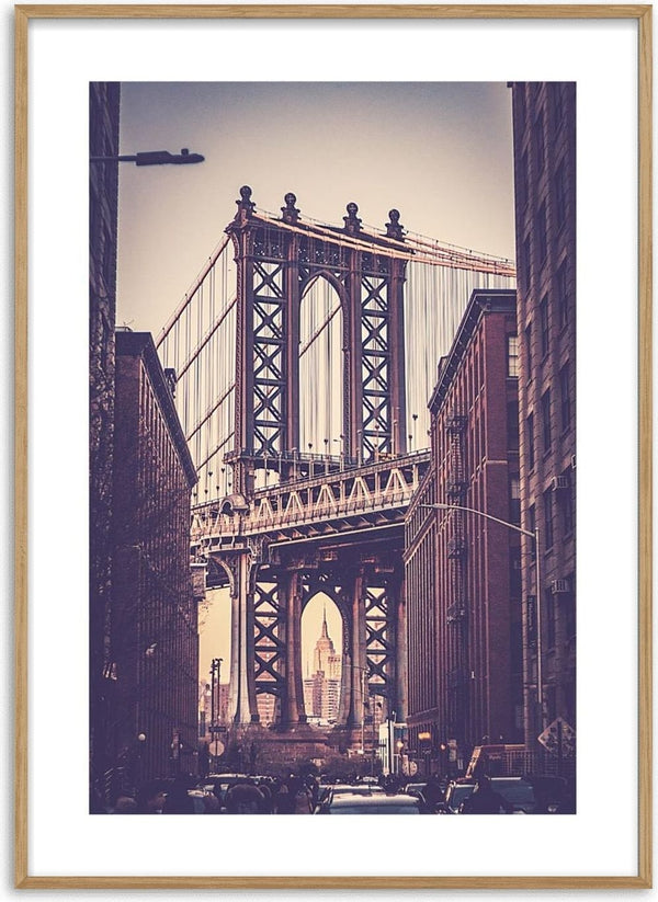 Vintage-style photo of the Brooklyn Bridge framed by city buildings, with the Empire State Building visible in the distance.